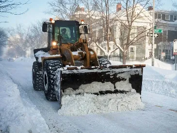 A snow-covered road with a snowplow clearing the accumulated snow.